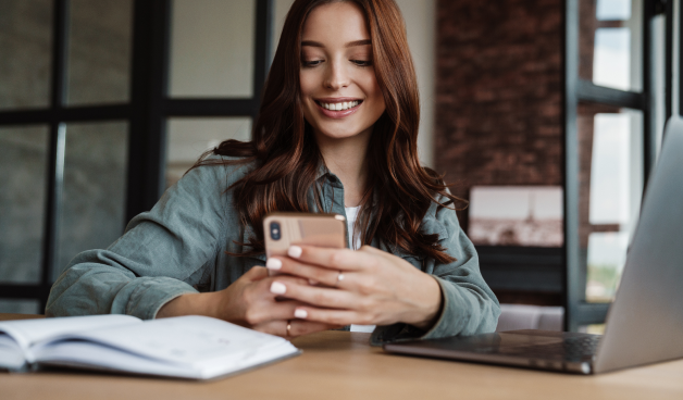 Mulher sorrindo enquanto olha para o smartphone.